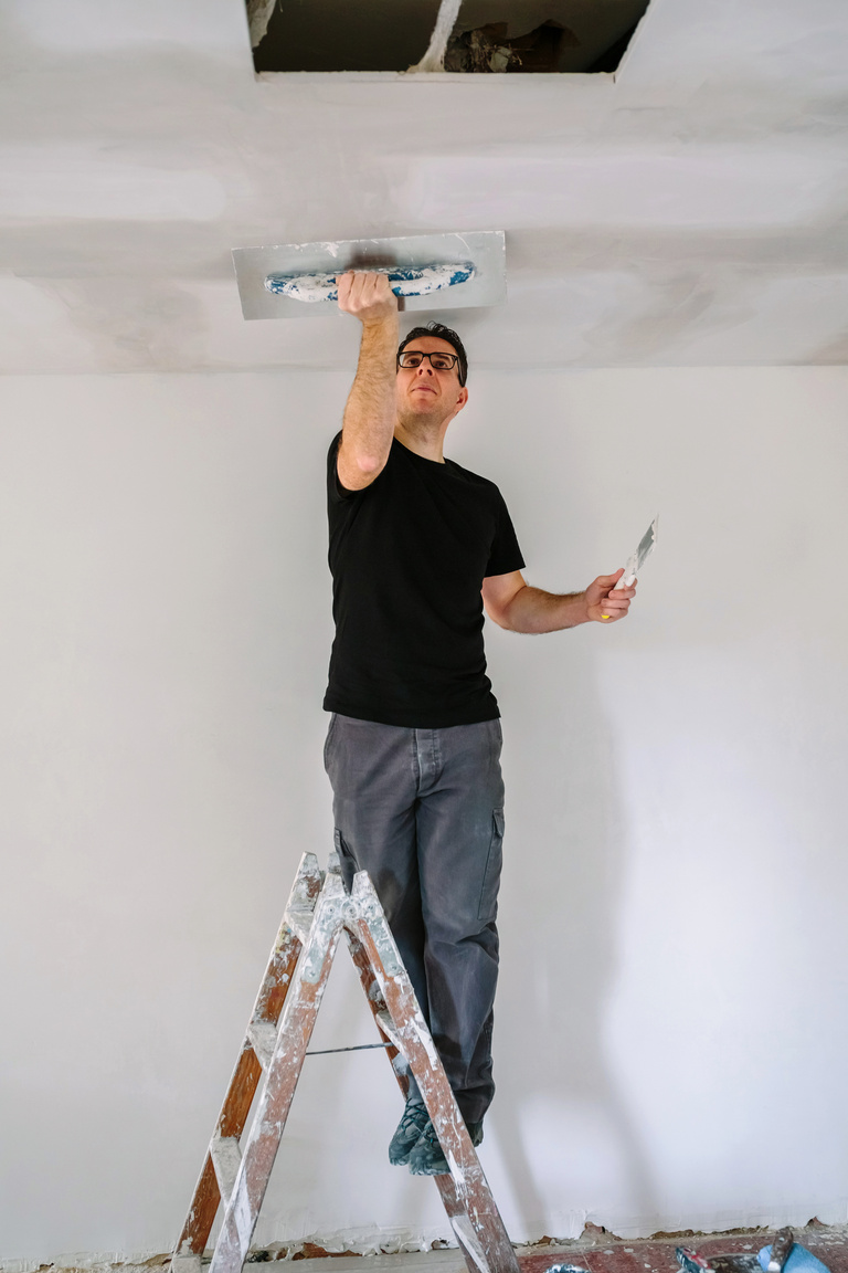 Plasterer Smoothing Plaster Ceiling with the Trowel